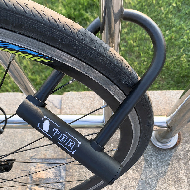 U-lock for bicycles, electric scooters, and motorcycles attached to a bicycle wheel with grass in the background